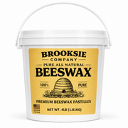 A white plastic bucket of Brooksie Company Pure All Natural Beeswax pastilles, featuring a large yellow label with black text and an illustration of a beehive.