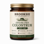Brooksie Company Grass Fed Colostrum 20% IgG dietary supplement in an 8 oz amber glass jar with a gold metal lid and cream-colored label.