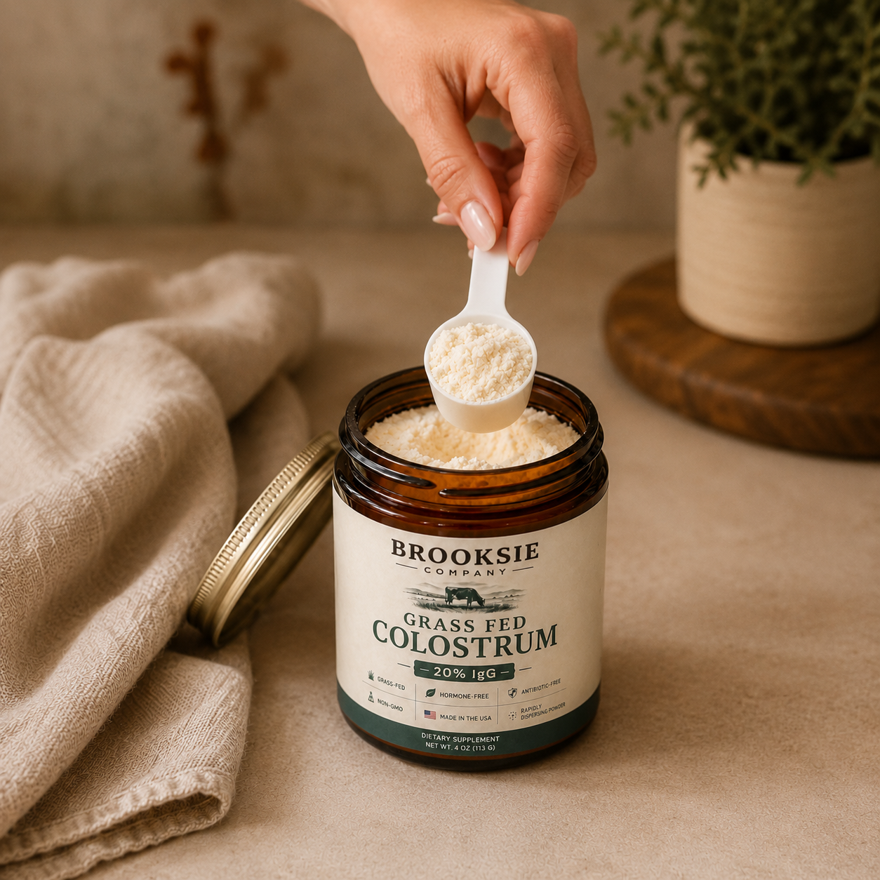 scooping brooksie company grass fed colostrum powder from amber jar